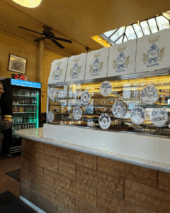 Interior counter and ordering area of a New York City pizza shop with menu signage
