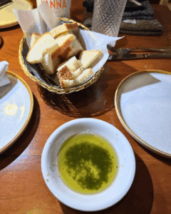 Bread basket served with olive oil for dipping on a wooden restaurant table