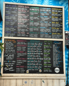Menu board displaying smoothie bowls, smoothies, and toppings at Playa Bowls