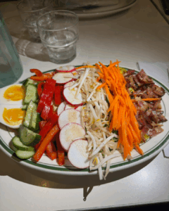Thai Cobb salad with fresh vegetables, soft-boiled eggs, bacon, and peanut dressing