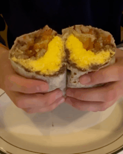 Breakfast burrito split open showing eggs, potatoes, and filling inside
