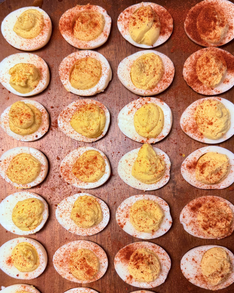 Classic deviled eggs arranged on a serving tray, topped with paprika