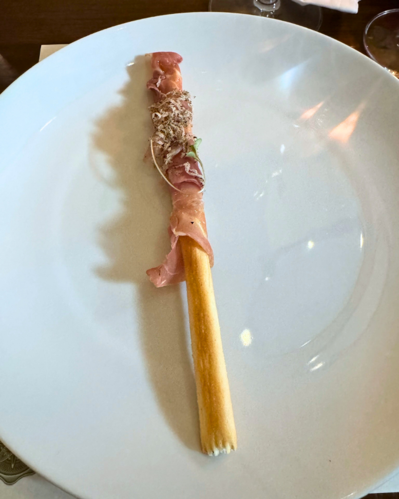 Prosciutto di Parma wrapped around a crispy breadstick with black truffle butter, served as the amuse-bouche at Amaro Supper Club in Fairhope.